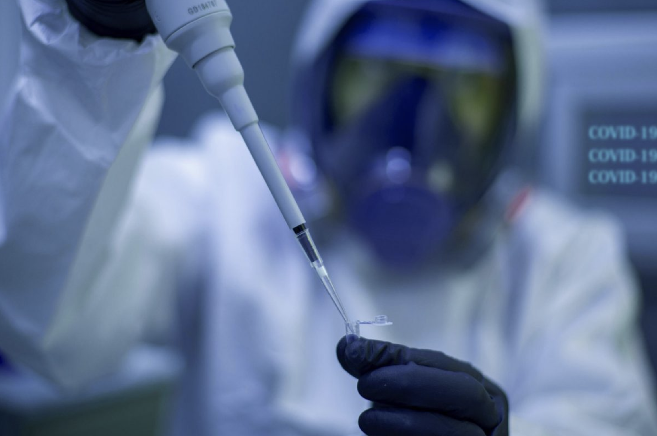 Scientifique en combinaison de protection manipulant un échantillon avec une pipette